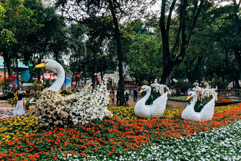 a bunch of fake swans sitting in the flowers