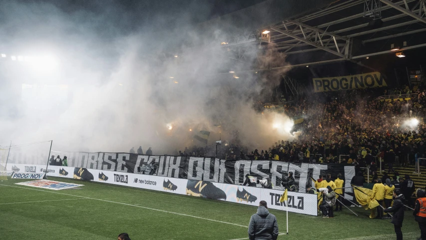 a soccer stadium filled with fans and flarers in the rain