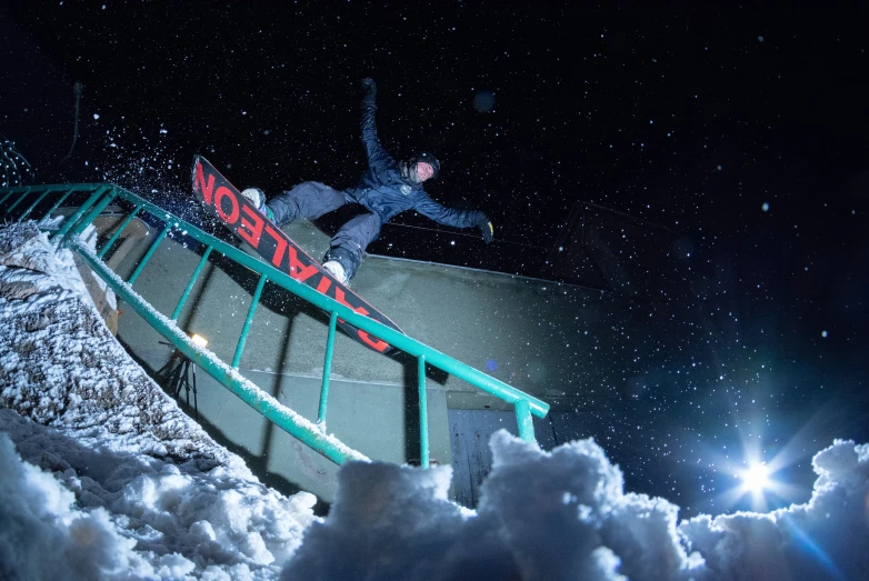 a person is snowboarding down a railing in the night