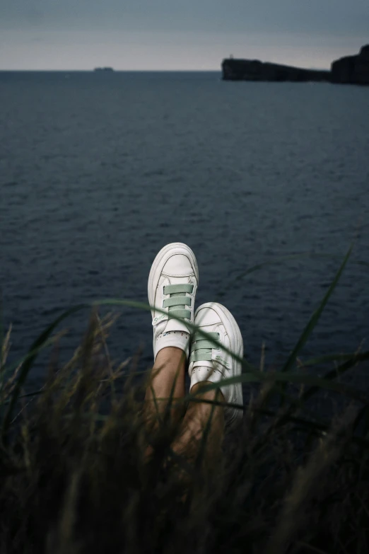 someone has their feet up in the grass by water