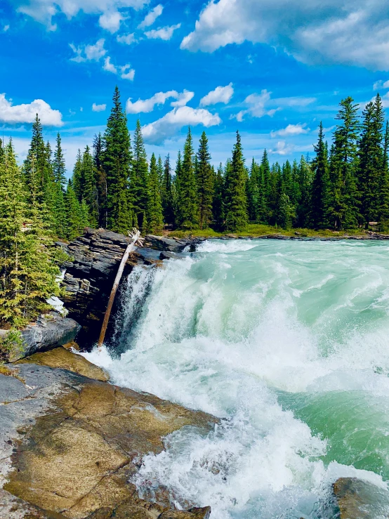 a man standing on top of a rock next to a waterfall