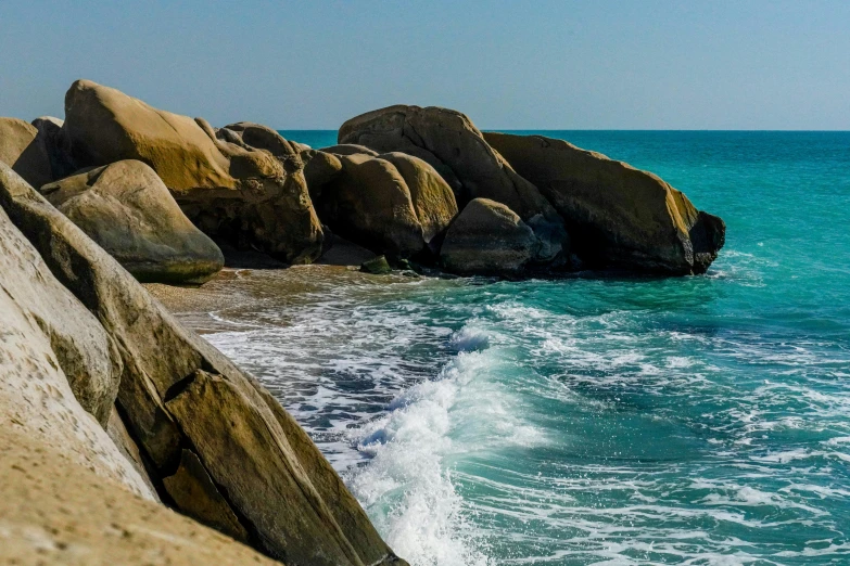 rocks on the shore of an ocean with waves crashing