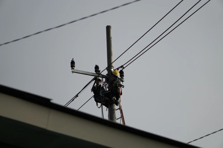 power lines, with utility equipment hanging from them and a man in safety gear working on the lines