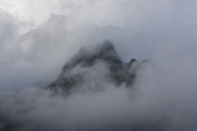 a mountain that is covered in clouds next to mountains