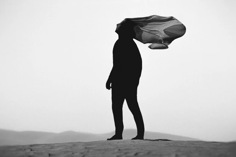 a person holding a umbrella while standing on top of a desert