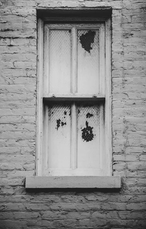 a window on a brick wall with the paint peeling off of it