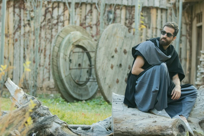 a man sitting on top of a tree trunk with an out door