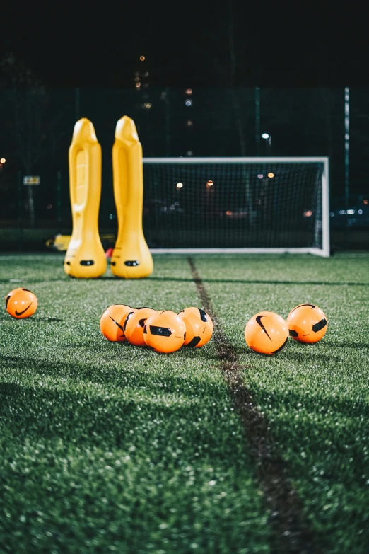 four plastic soccer balls laying on a green grass field