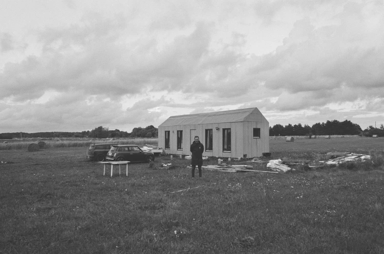 a man is standing in a field by a white building