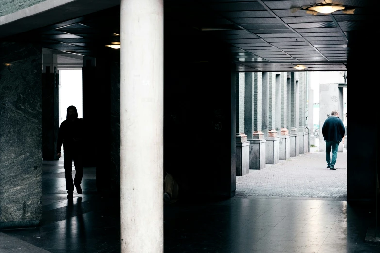 two people are walking in a building, near pillars and columns