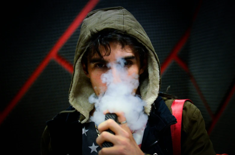 young man smoking in a hooded jacket with american flag