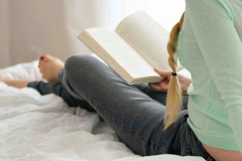 a girl laying on a bed reading a book