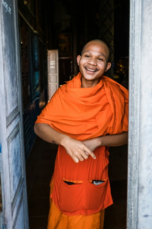 a smiling monk poses with his arms crossed