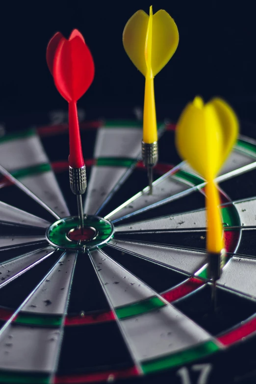 three red and yellow darts on a dart board