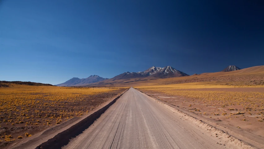 a dirt road leads through an empty mountain range