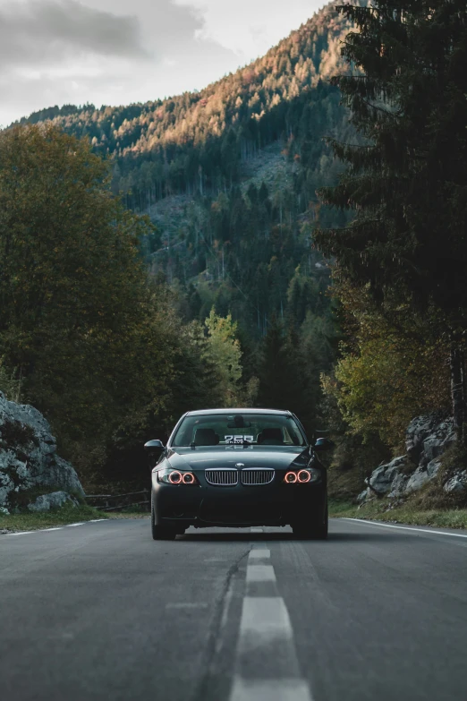 black car driving down a road with the mountains in the back