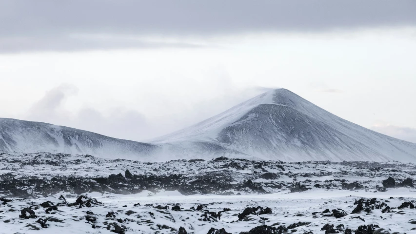 a hill range covered in snow under a cloudy sky