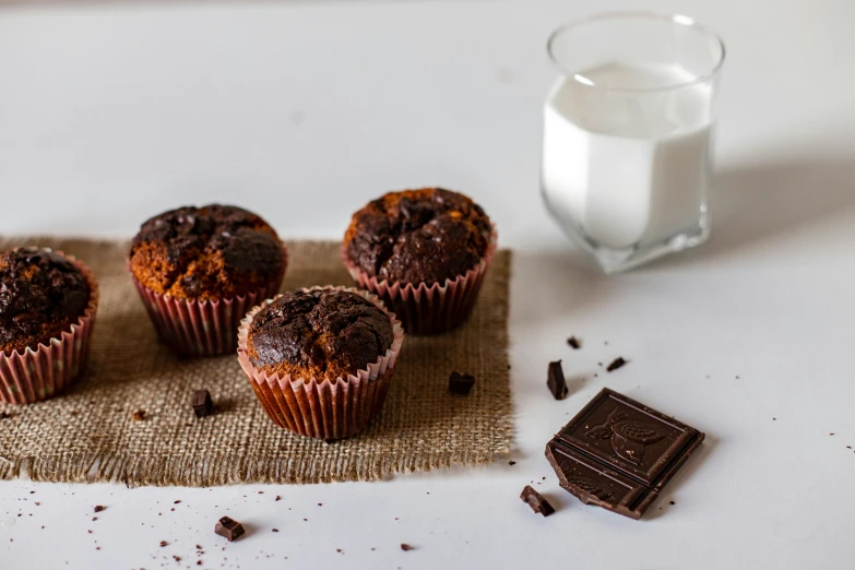 four chocolate muffins are sitting on a towel with a bite taken out