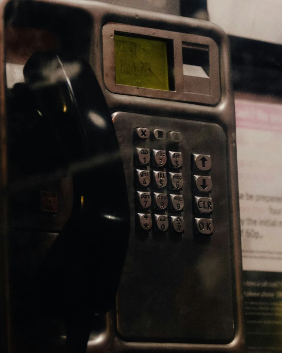 the old pay phone is black and it has a yellow display