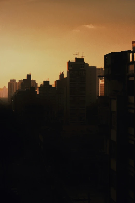 a sunset is behind silhouettes of tall buildings
