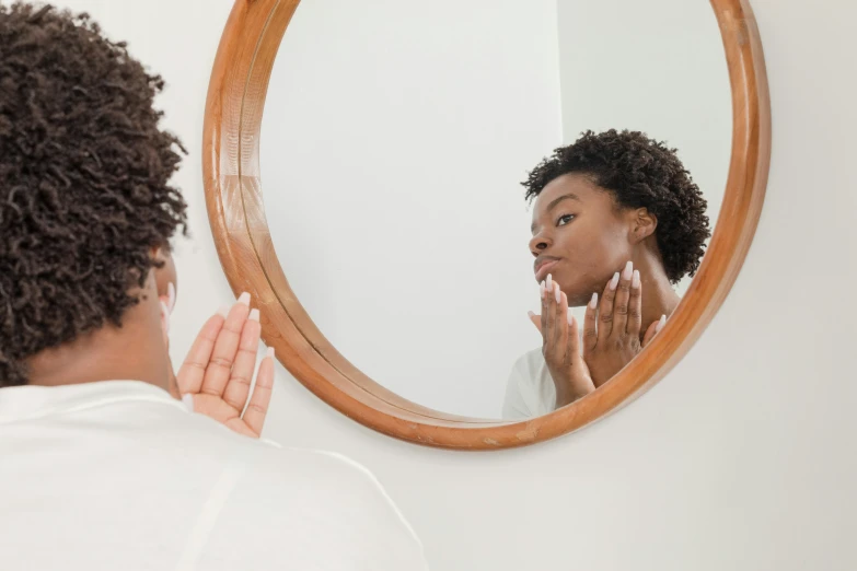 woman washing her face with hand in front of the mirror