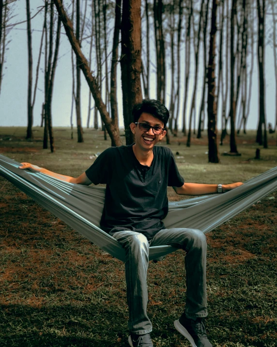 a man sitting in a hammock surrounded by trees