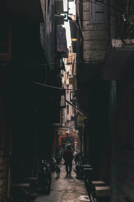 a man walking down a narrow alleyway between buildings