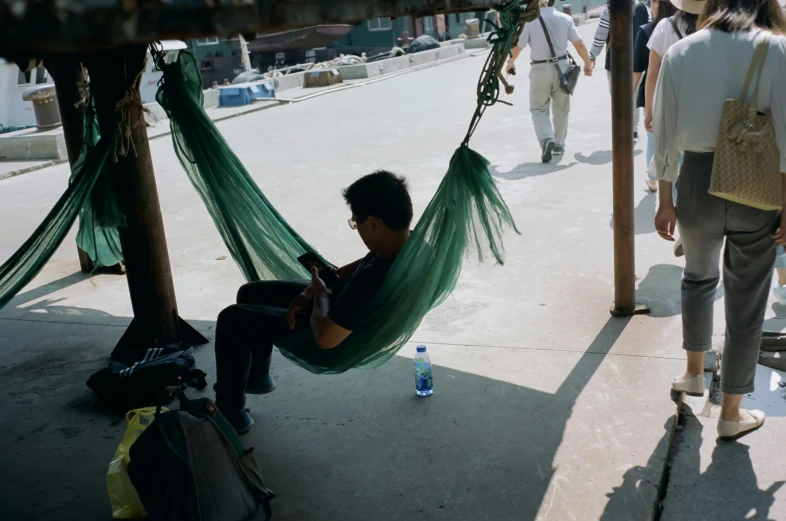 a man sitting on a hammock while on his cell phone