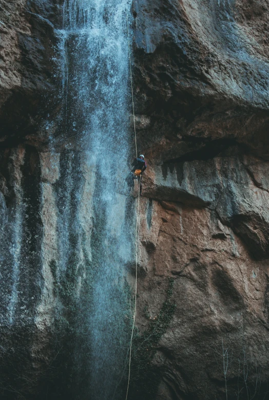 a man standing at the base of a waterfall