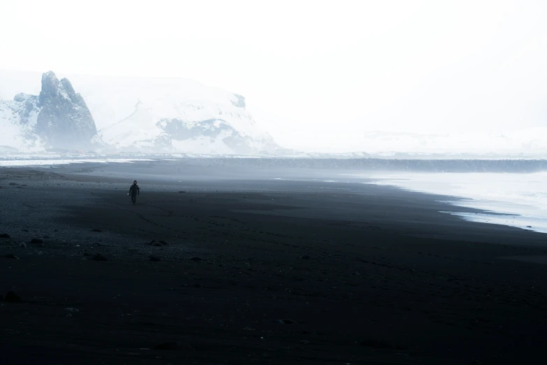 two people stand alone on the sand and water