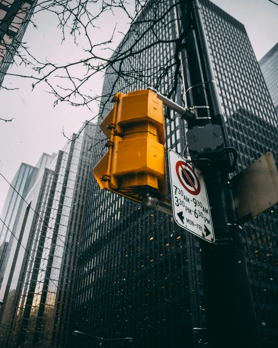 a yellow traffic light hanging from a pole in a big city