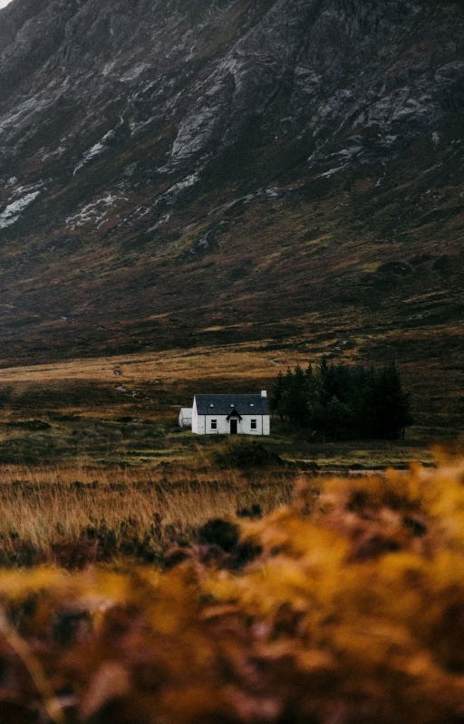 a white building stands in a field near mountains