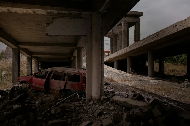 a small red car abandoned by the side of a road