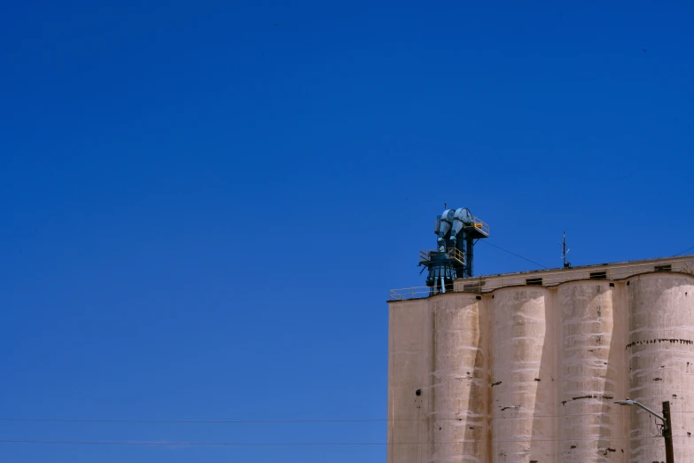 a big silo with people on top and some buildings behind it