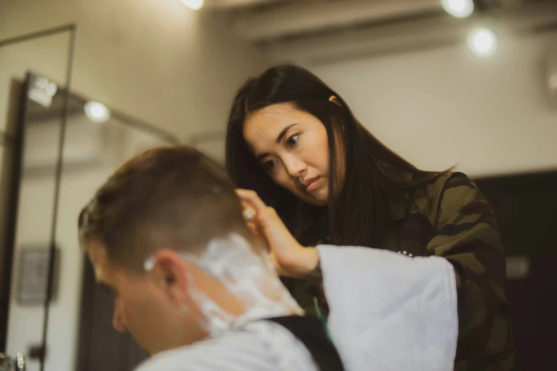 a woman is having her hair cut by another man