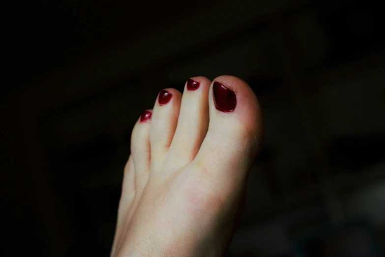 a person with red nail polish on their toes