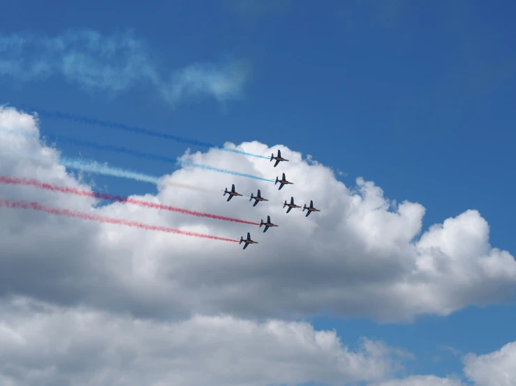 four planes flying in formation in front of some fluffy clouds