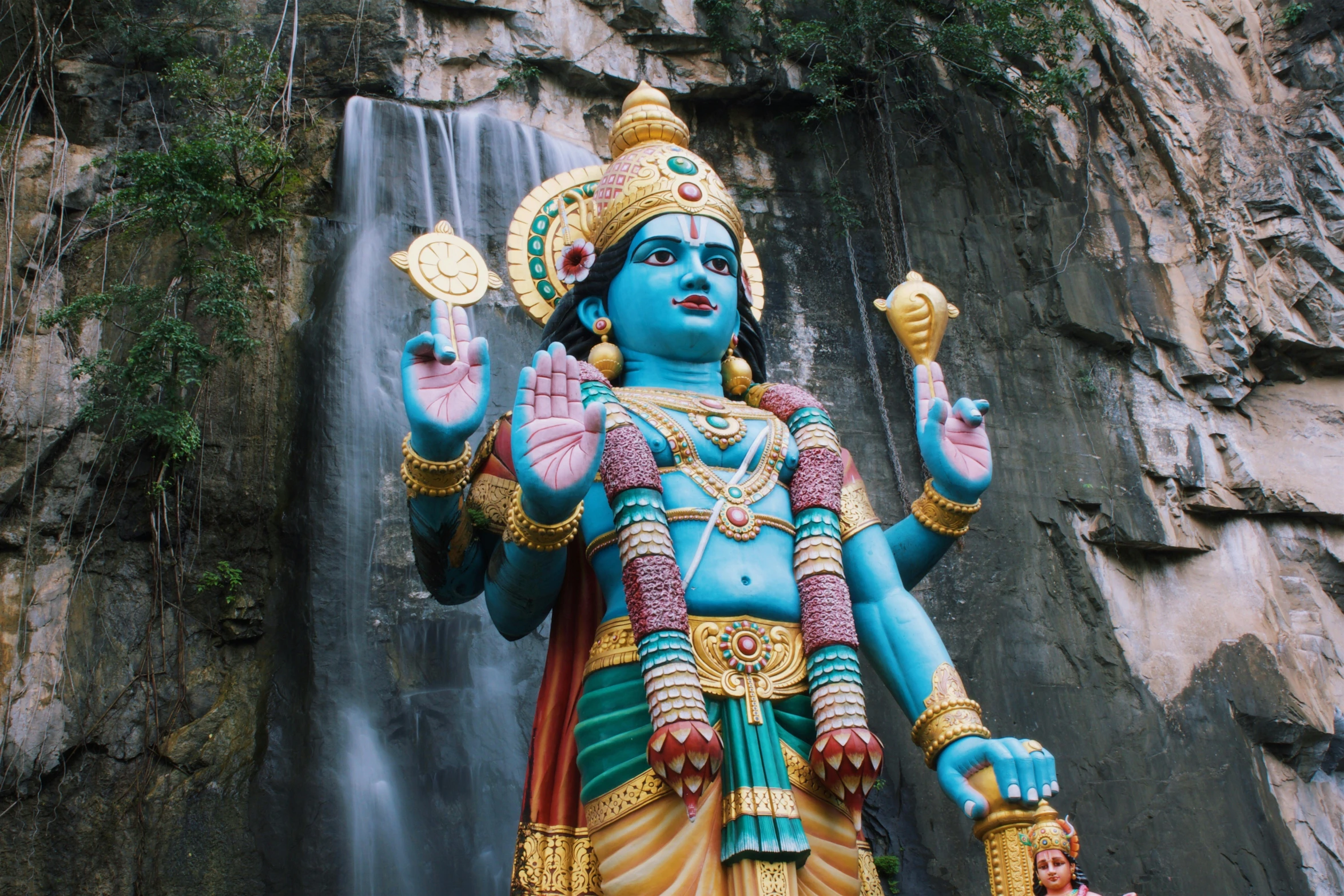 statue with large body in front of large waterfall