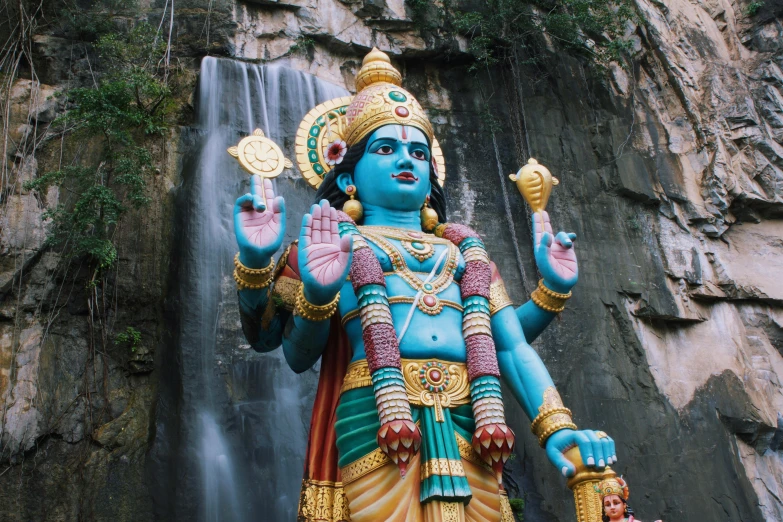 statue with large body in front of large waterfall