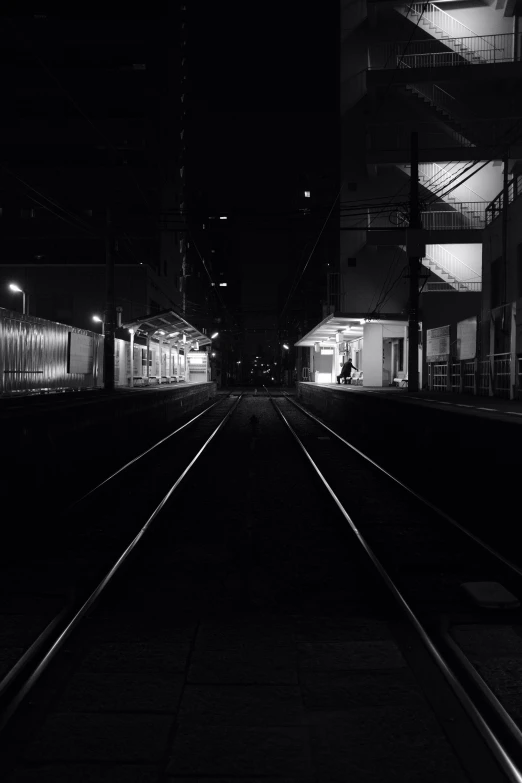 dark night with tracks leading to buildings and light poles