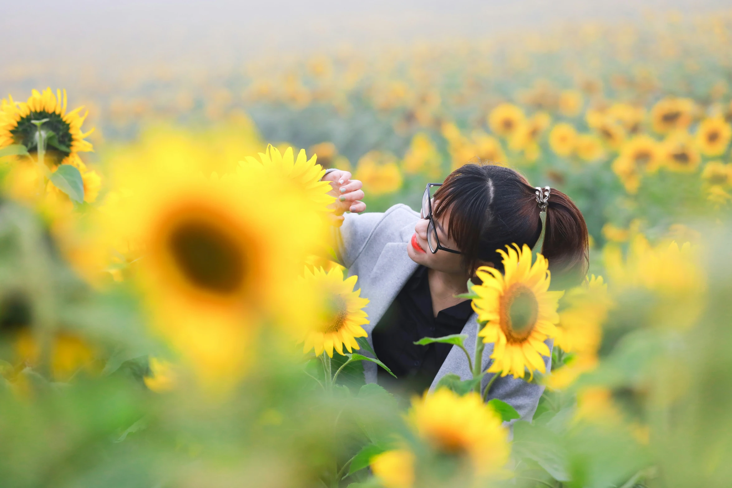 a person hiding behind a sunflower, and looking at the other one