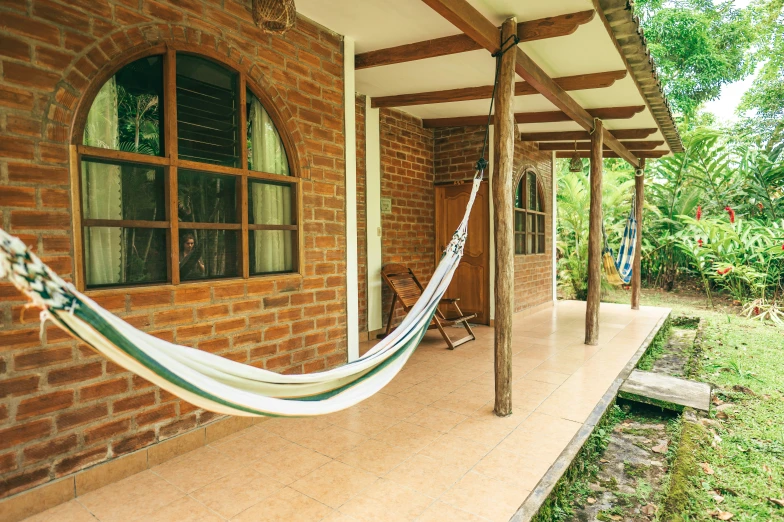 a porch with wood and brick columns and hammock on the side