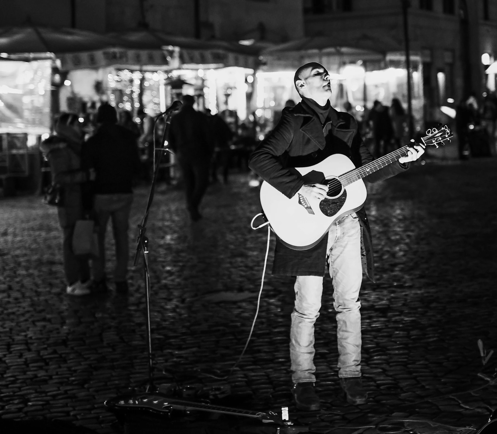 man standing on the side of a street with an acoustic guitar