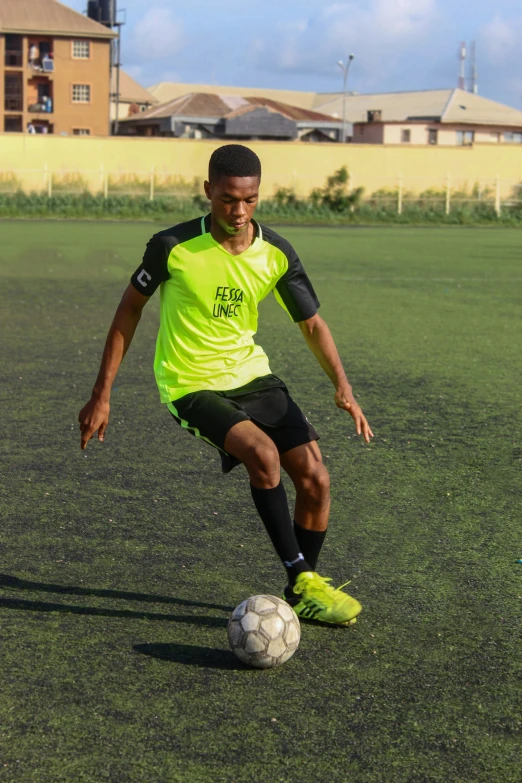 man in neon yellow uniform kicking a soccer ball