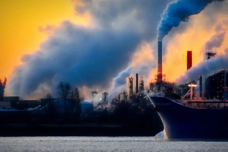 an industrial area with smoke stacks, chimneys and boats