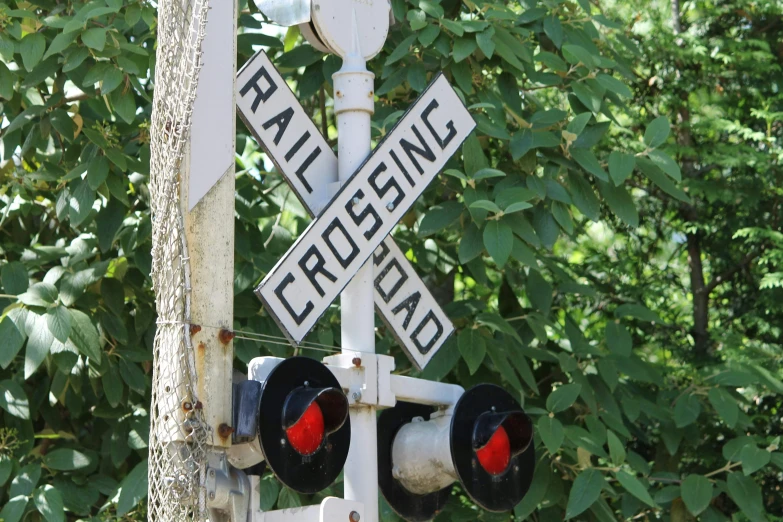 street signs and stop lights are displayed on a railroad crossing