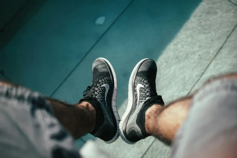 a man wearing vans sneakers standing on a sidewalk