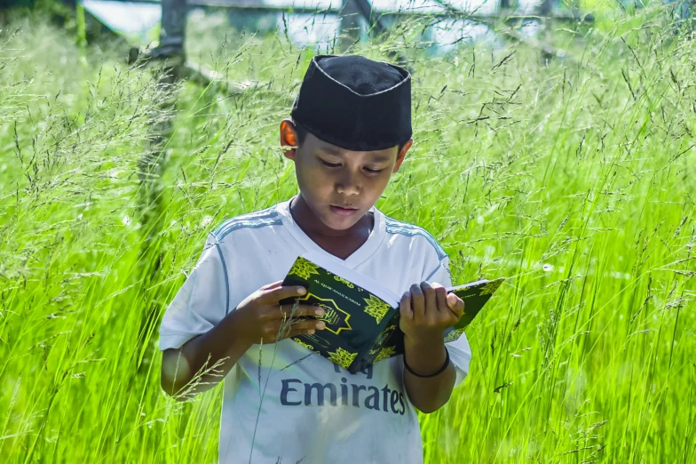 a  standing in tall green grass looking at a small tablet