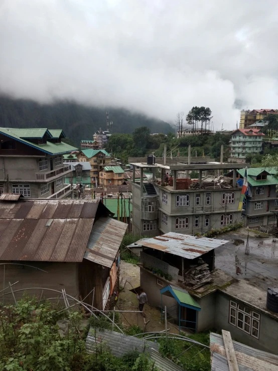 buildings with green roofs on a hill with low cloud in the background