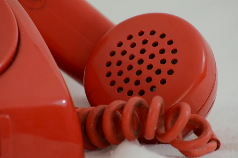 a red colored telephone receiver has a wire coming out